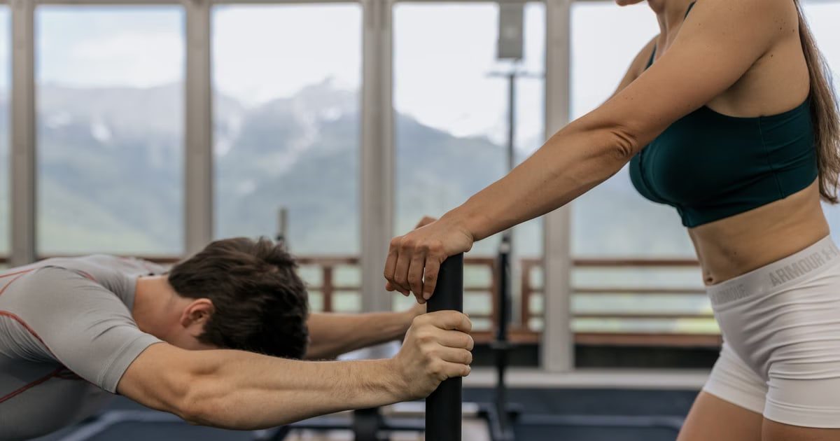 A couple working out together at an indoor gym with mountain views.
