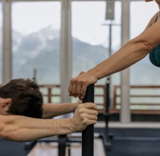 A couple working out together at an indoor gym with mountain views.
