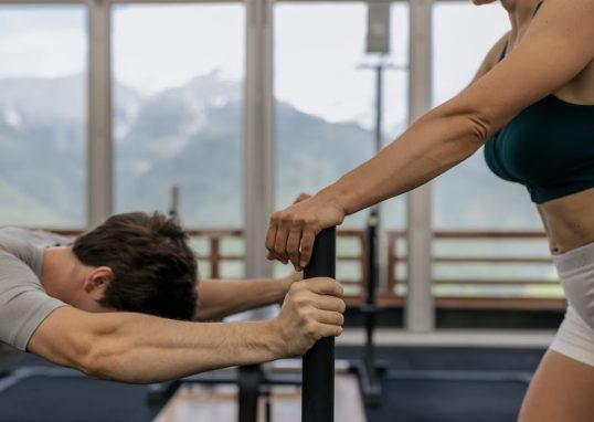 A couple working out together at an indoor gym with mountain views.